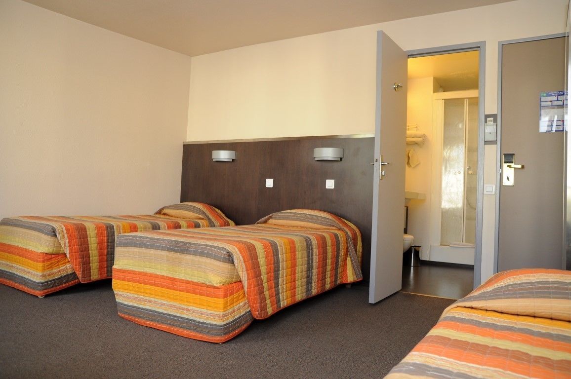 Ein Hotelzimmer mit zwei Betten, einem Badezimmer und einer Tür zu einem weiteren Raum.