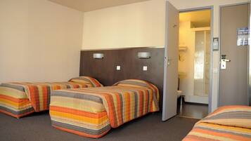 Ein Hotelzimmer mit zwei Betten, einem Badezimmer und einer Tür zu einem weiteren Raum.