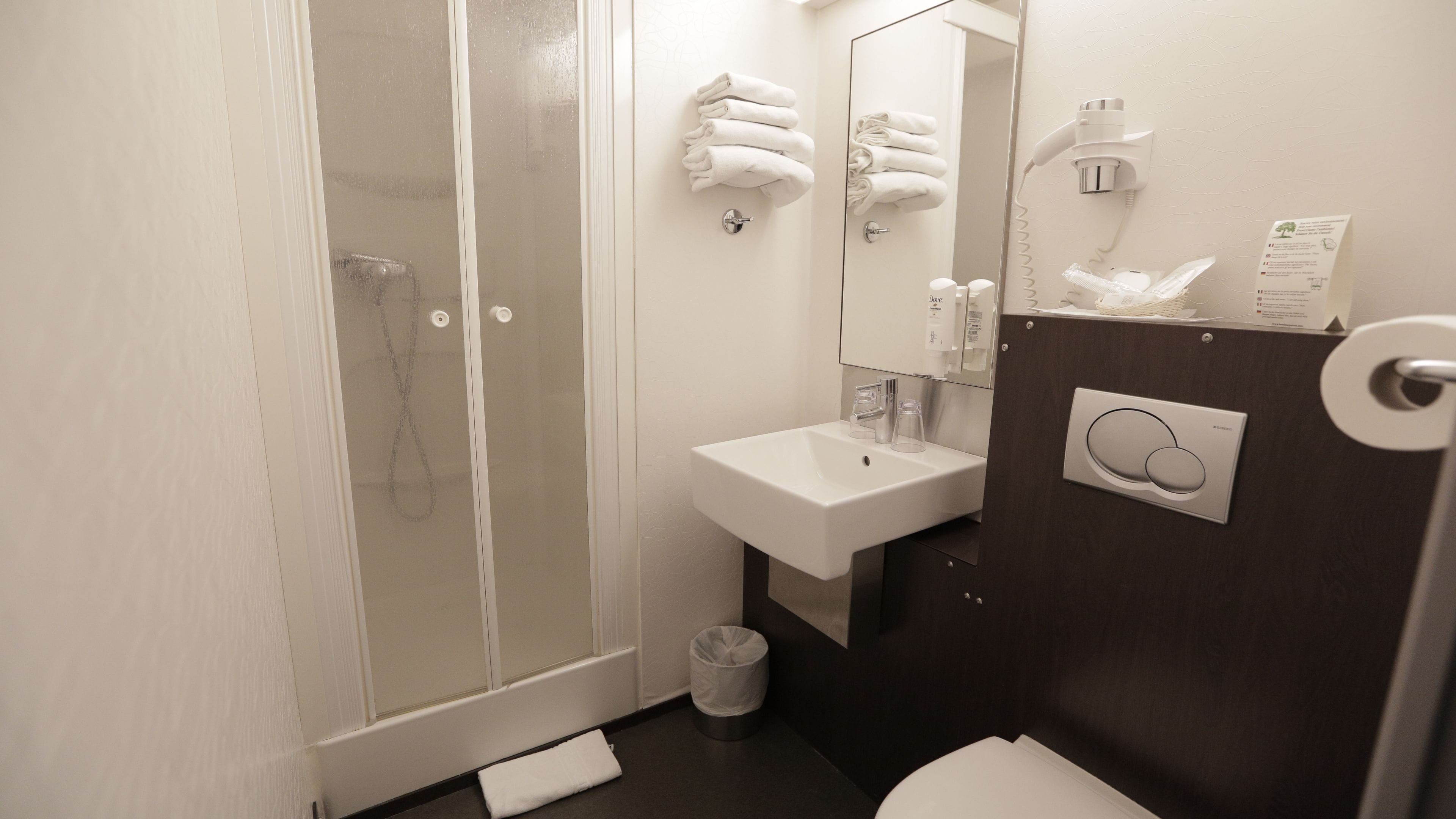A modern bathroom with a glass shower enclosure, a white sink, and a dark wooden vanity.