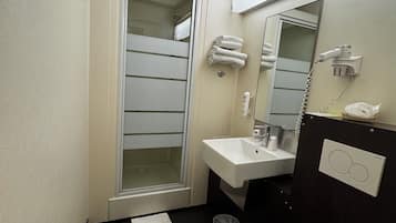 A compact bathroom with a white toilet, a sink, a mirror, and a towel rack.