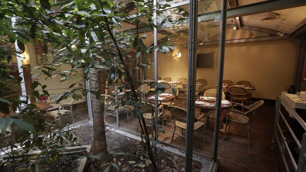 A restaurant with wicker furniture and a glass enclosure. - Hôtel Au Petit Caporal (Maisons-Alfort)