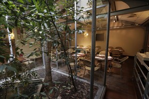 Een restaurant met rieten meubels en een glazen overkapping.
