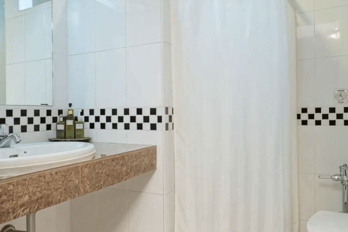 A bathroom with a white sink, a mirror, and a shower curtain.