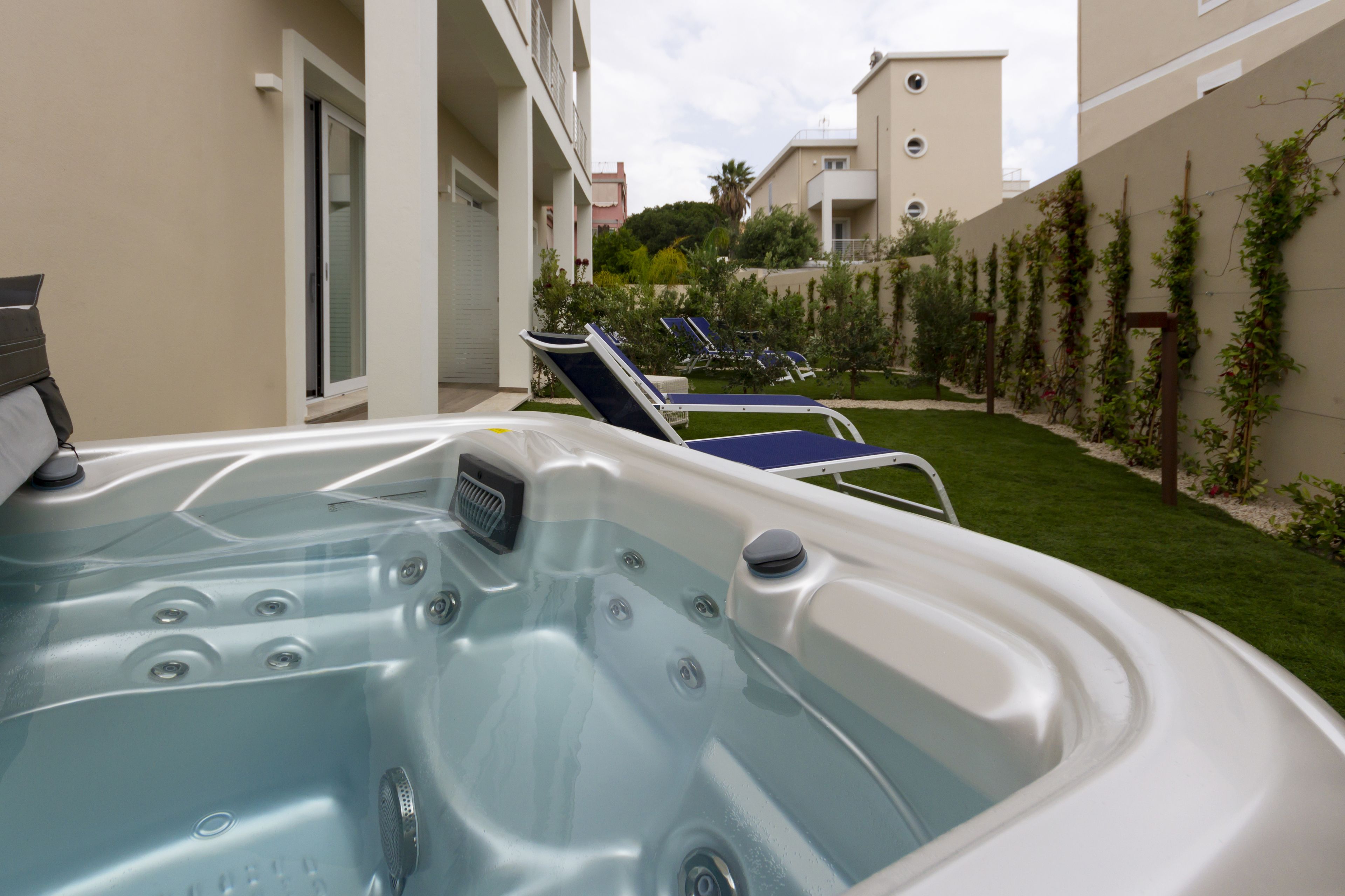 Un bain à remous avec vue sur un jardin et un bâtiment en arri ère-plan.