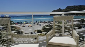 Een balkon met rieten stoelen met uitzicht op een strand.