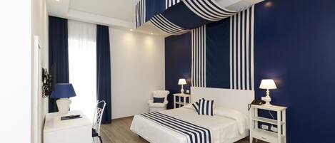 A modern bedroom with a large bed, bedside tables with lamps, a chair, and a desk with a lamp.