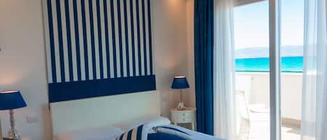 A bedroom with a large bed, a view of the sea, and a balcony.