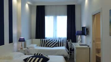 A hotel room with two beds, a desk, a chair, a TV, and a bathroom.