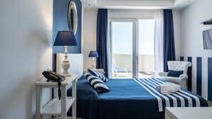 Een hotelkamer met een bed, nachtkastje met lamp, stoel en uitzicht op het omliggende landschap.
