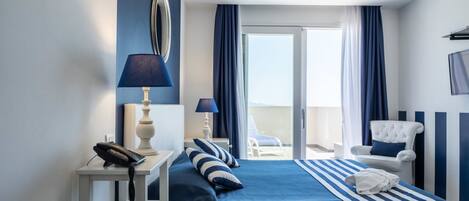 A hotel room with a bed, a bedside table with a lamp, a chair, and a view of the outdoors.