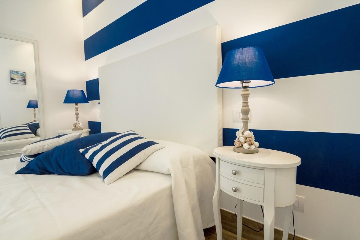A bedroom with a bed, two bedside tables, and a mirror.
