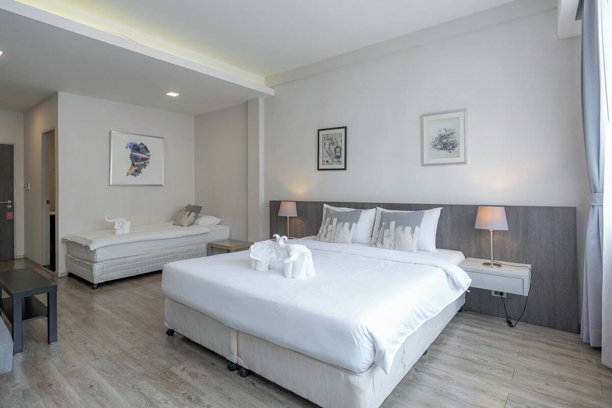 A modern hotel room with a large bed, bedside tables, and artwork on the walls.