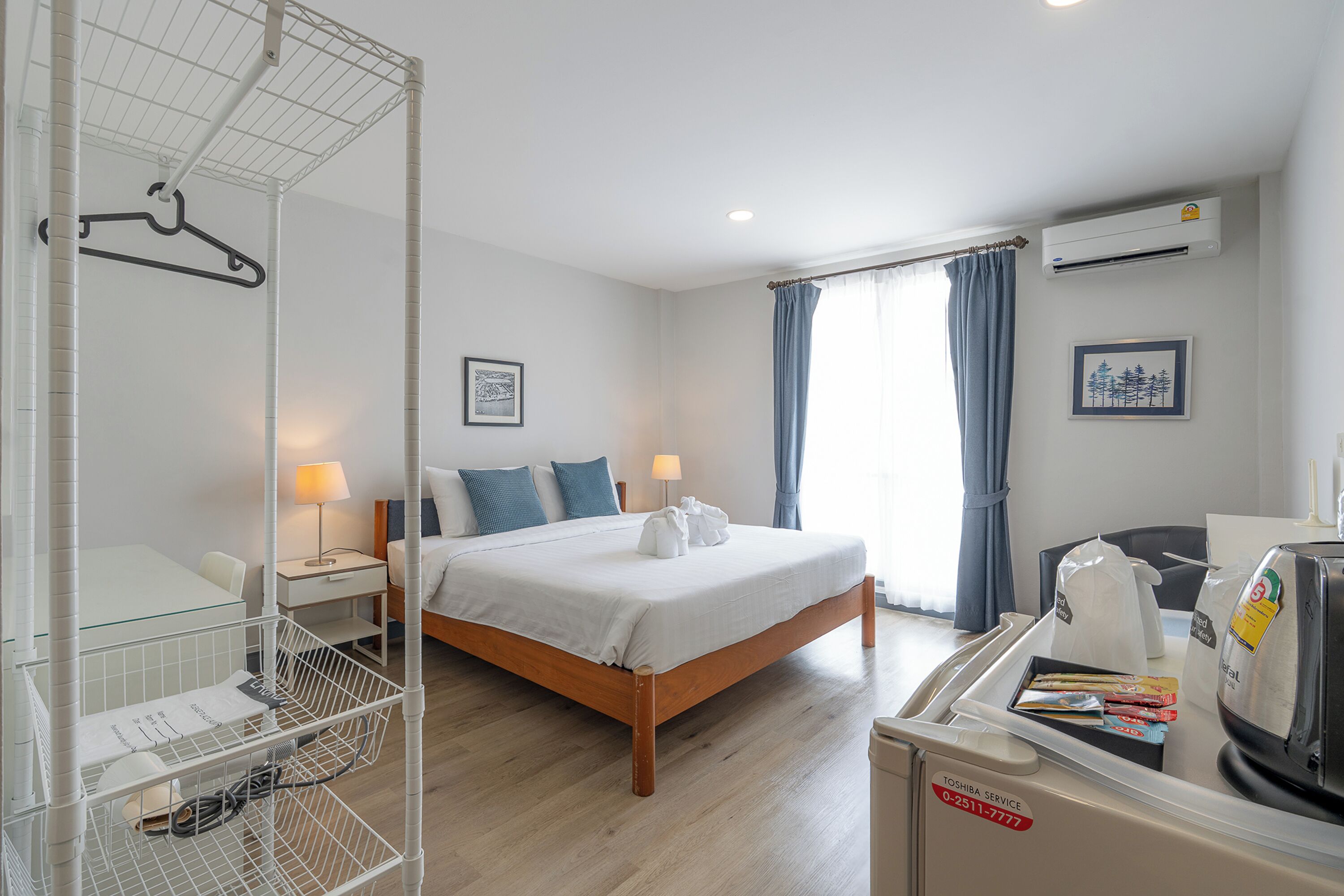 Une chambre d’hôtel comprenant un lit, des tables de chevet, un espace douche et une kitchenette.