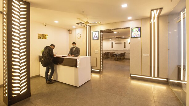A reception area with a reception desk, a clock, and a framed picture on the wall. - Airport Hotel Chanakya (New Delhi)