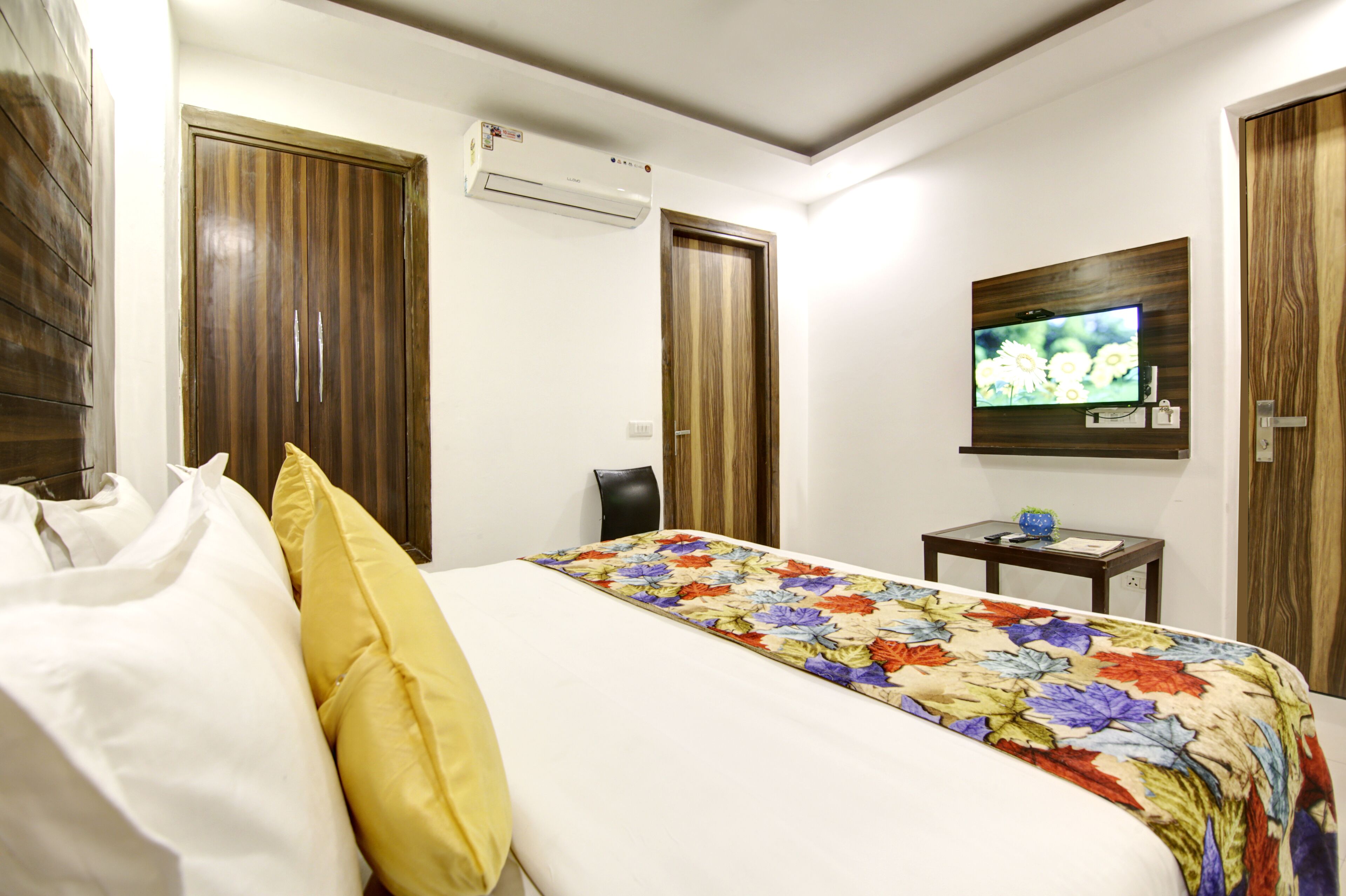 A hotel room with a bed, a TV mounted on the wall, and a small table with a globe.
