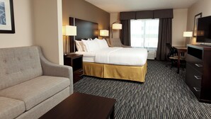 A hotel room with a bed, a sofa, a desk, and a television. - Holiday Inn Express & Suites Omaha South - Ralston Arena by IHG (Omaha)