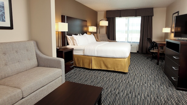 Ein Hotelzimmer mit Bett, Sofa, Schreibtisch und Fernseher.