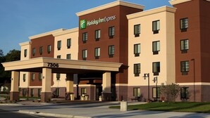 A Holiday Inn Express building with a beige and brown facade, multiple windows, and a clear sky. - Holiday Inn Express & Suites Omaha South - Ralston Arena by IHG (Omaha)