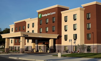 Un bâtiment de l’hôtel Holiday Inn Express avec une façade beige et marron, de nombreuses fenêtres et un ciel dégagé.