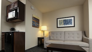 Ein Hotelzimmer mit Küchenzeile, einer Couch, einer Lampe und einem gerahmten Bild an der Wand.