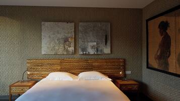 A bedroom with a large bed, wooden headboard, two bedside tables, and artwork on the walls.