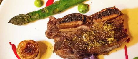 A plate with a steak, asparagus, and a purple vegetable, possibly a beetroot, with some sauce and a small onion ring.