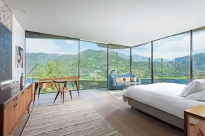 A bedroom with a large window, a bed, a desk with a chair, and a blue bean bag. - Vik Chile (San Vicente)