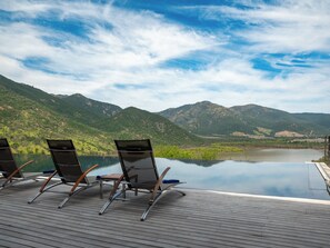A deck with lounge chairs overlooking a lake and mountains. - Vik Chile (San Vicente)