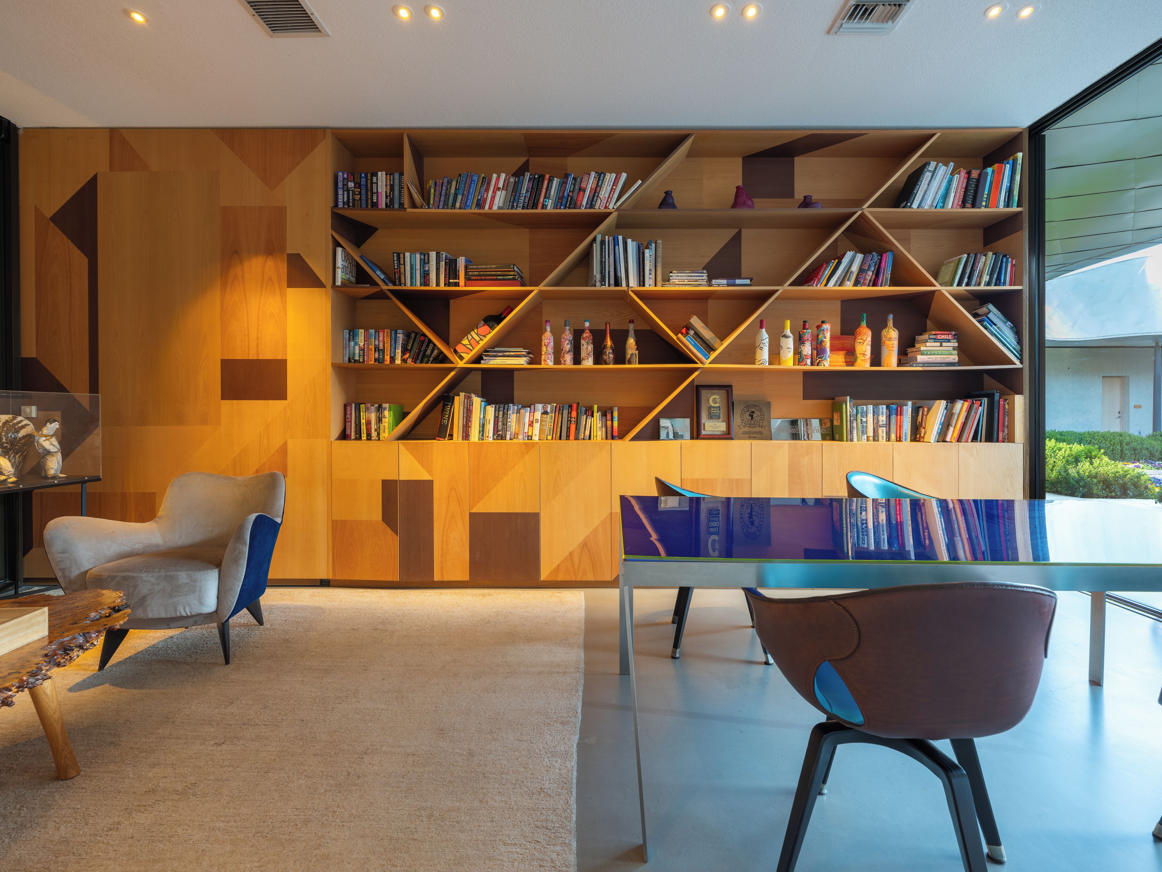 Una biblioteca moderna con un diseño geométrico para las estanterías, un área de descanso acogedora y vistas despejadas al exterior.