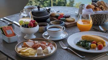 Una mesa de desayuno con diferentes alimentos, una tetera y una taza de café.