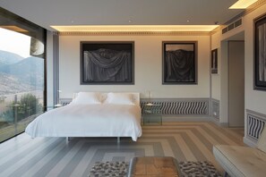 Un dormitorio moderno con una cama grande, vistas a las montañas y un balcón.