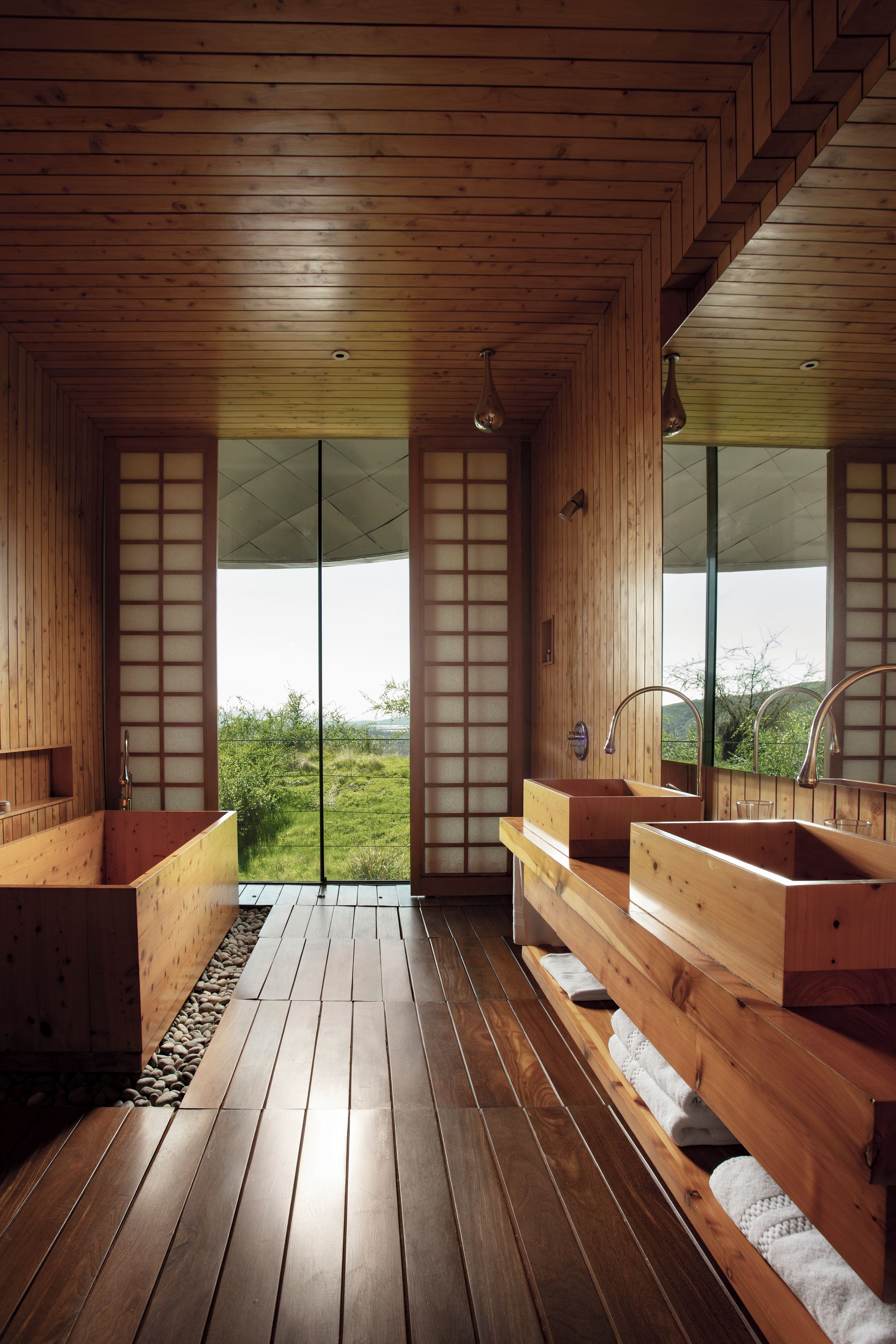A wooden interior with a large window, wooden flooring, and a sink.