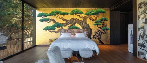 A bedroom with a large bed, a wooden ceiling, and a wall mural of trees.