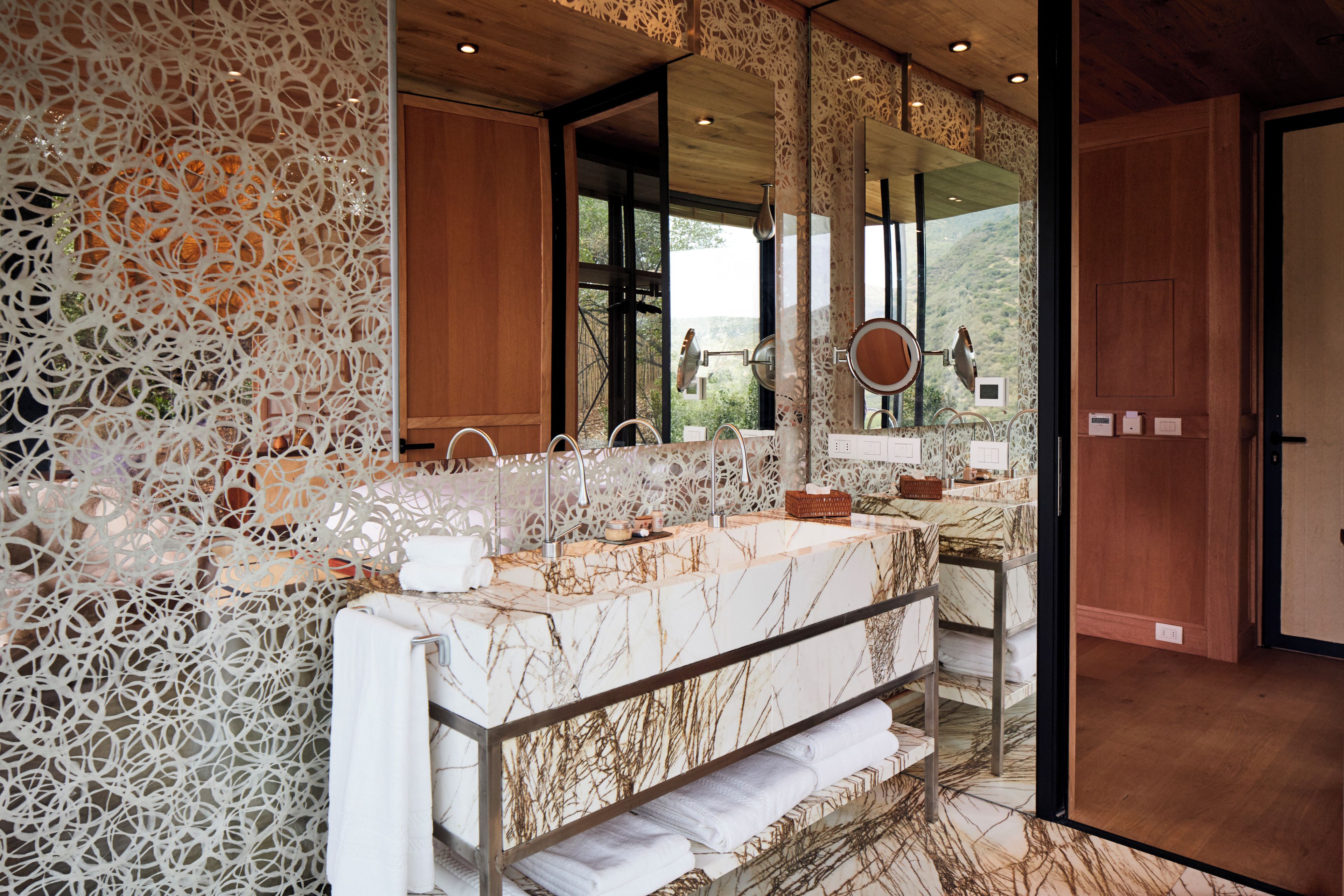 A modern bathroom with a marble vanity, large mirrors, and a decorative wall.