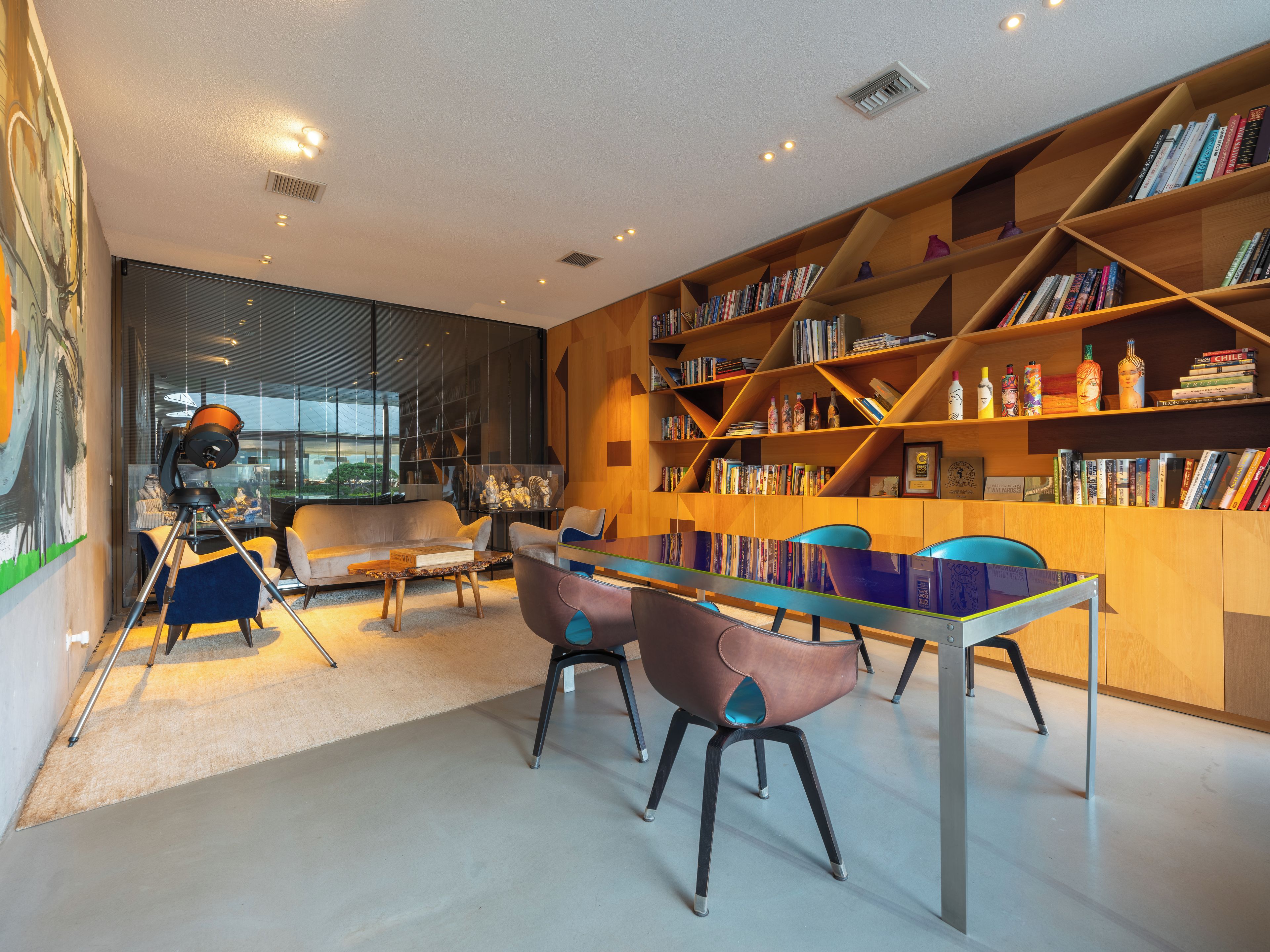 Una biblioteca moderna con estanterías, un telescopio y asientos cómodos.