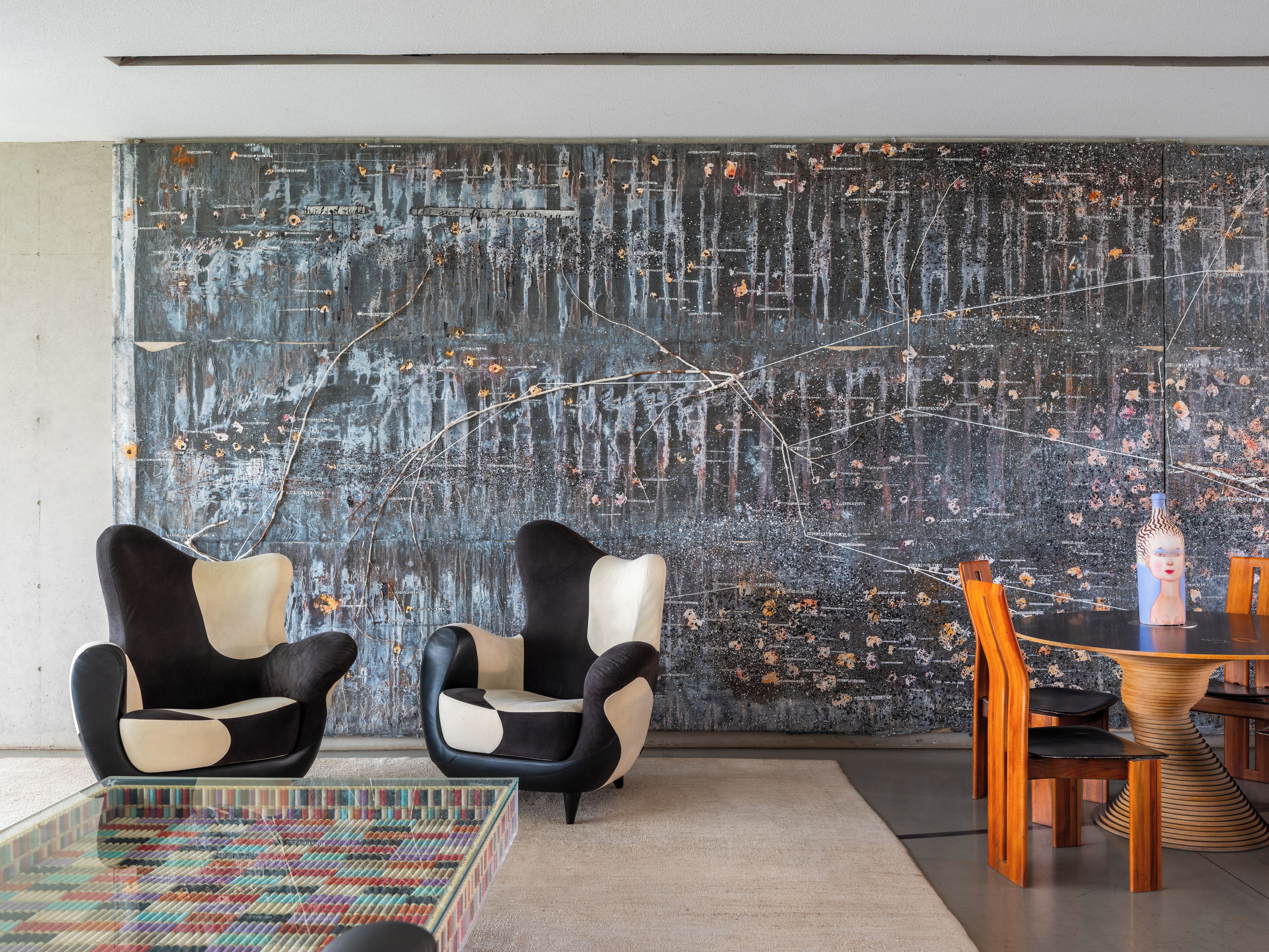 Un interior moderno con dos sillones blanco y negro, una mesa de centro de cristal y una mesa de comedor de madera con sillas.