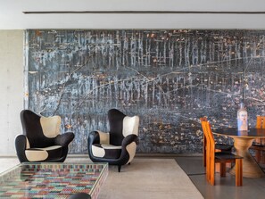Un interior moderno con dos sillones blanco y negro, una mesa de centro de cristal y una mesa de comedor de madera con sillas.