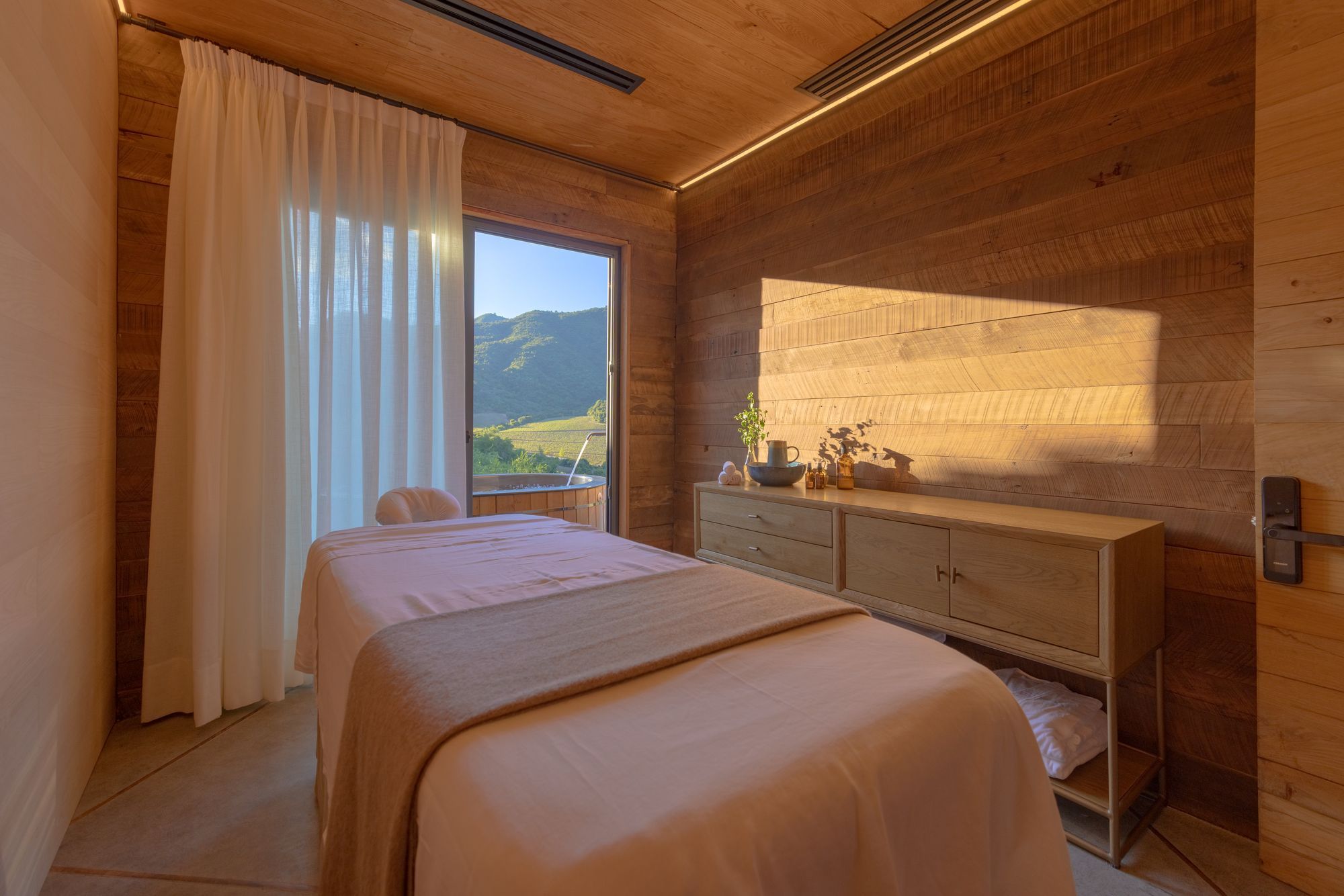 Une chambre à coucher avec un lit, une table de chevet et une vue sur un paysage par la fenêtre.