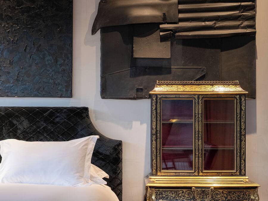 A bedroom with a bed, a decorative cabinet, and a modern abstract painting on the wall.