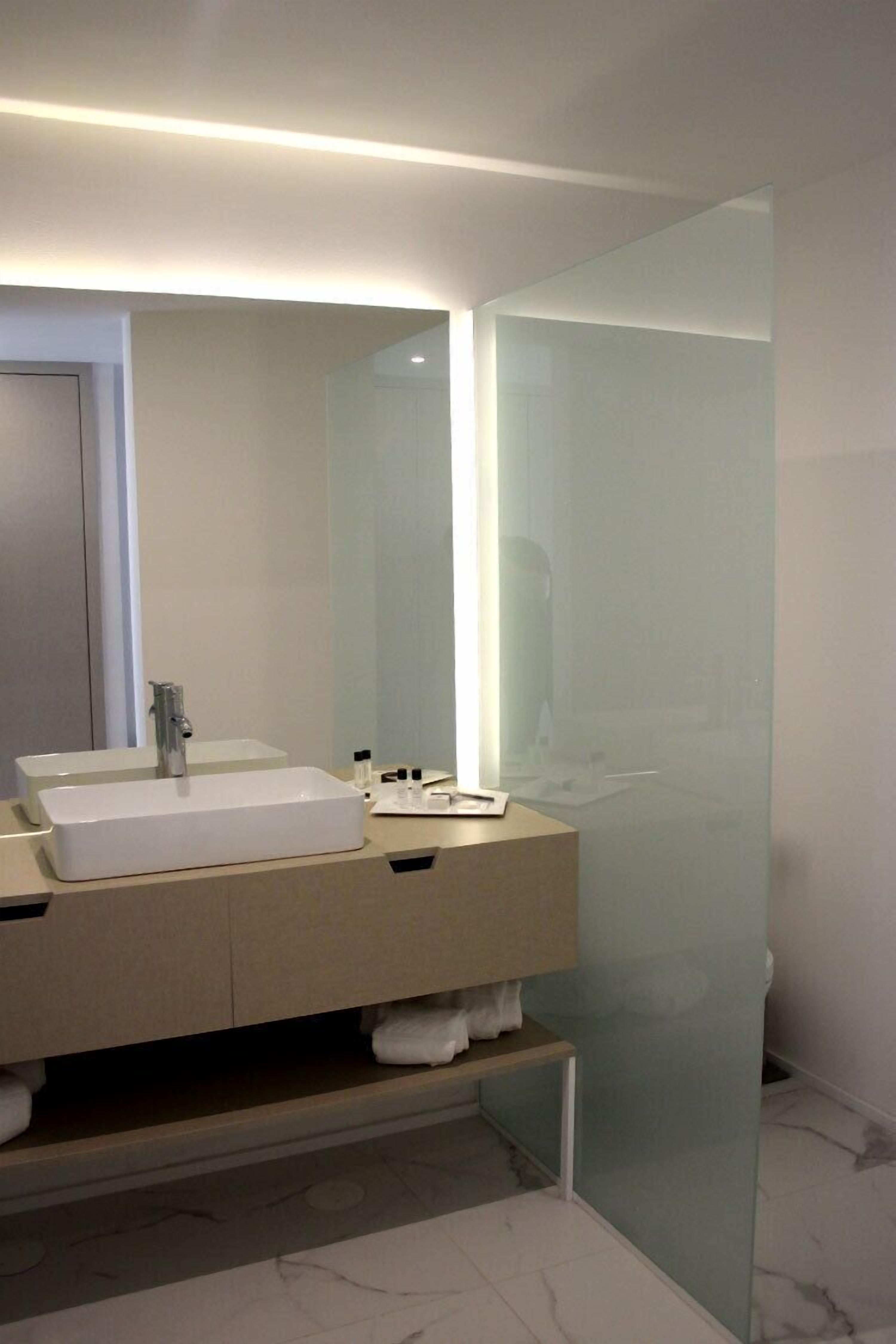 A modern bathroom with a dual sink vanity, a glass shower enclosure, and a marble-tiled floor.