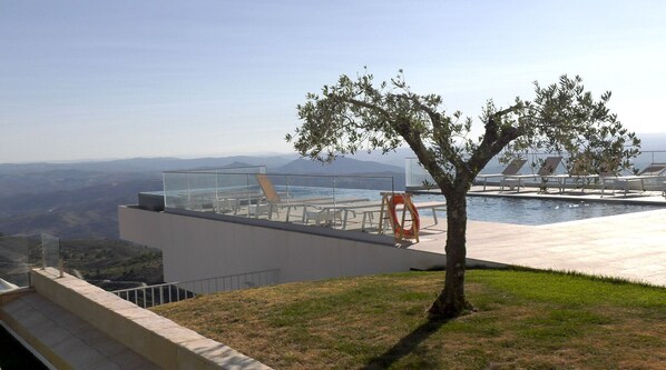 A rooftop pool area with a clear view of the surrounding landscape, a lifebuoy, and a tree.