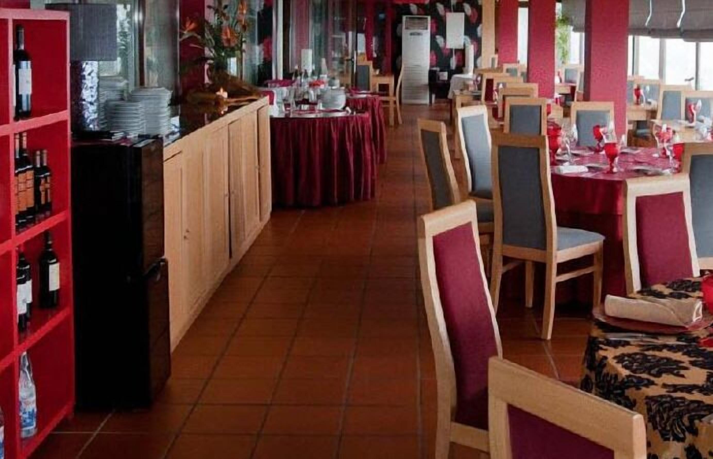 Un restaurant amb caires i taules de fusta, cortines vermelles i un paviment de rajoles.