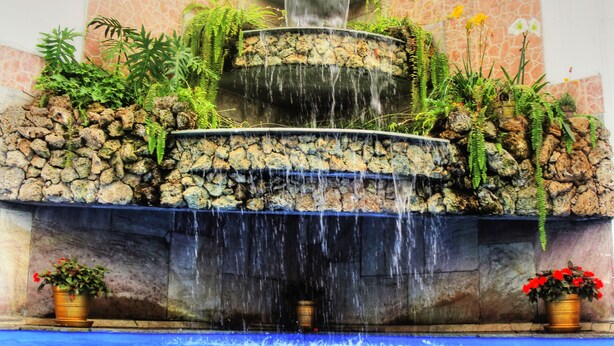 A multi-tiered waterfall fountain with surrounding greenery and a pool at the base. - Miraflores Colon Hotel (Lima)