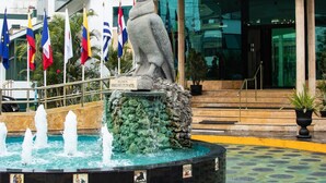 A hotel entrance with a fountain, flags, and a bird statue. - Miraflores Colon Hotel (Lima)