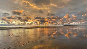 A beach with a wet sand surface reflecting the sky.