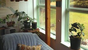 A cozy room with a striped sofa, a hanging lantern, and a view of greenery outside. - Whalesong Bed and Breakfast (Homer)