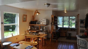 A cozy kitchen with wooden furniture, a dining table, and a refrigerator. - Whalesong Bed and Breakfast (Homer)