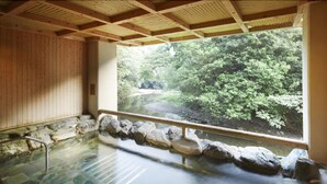 A traditional Japanese onsen with a view of a forested area through a large window. - Fudouguchikan (Izumisano)