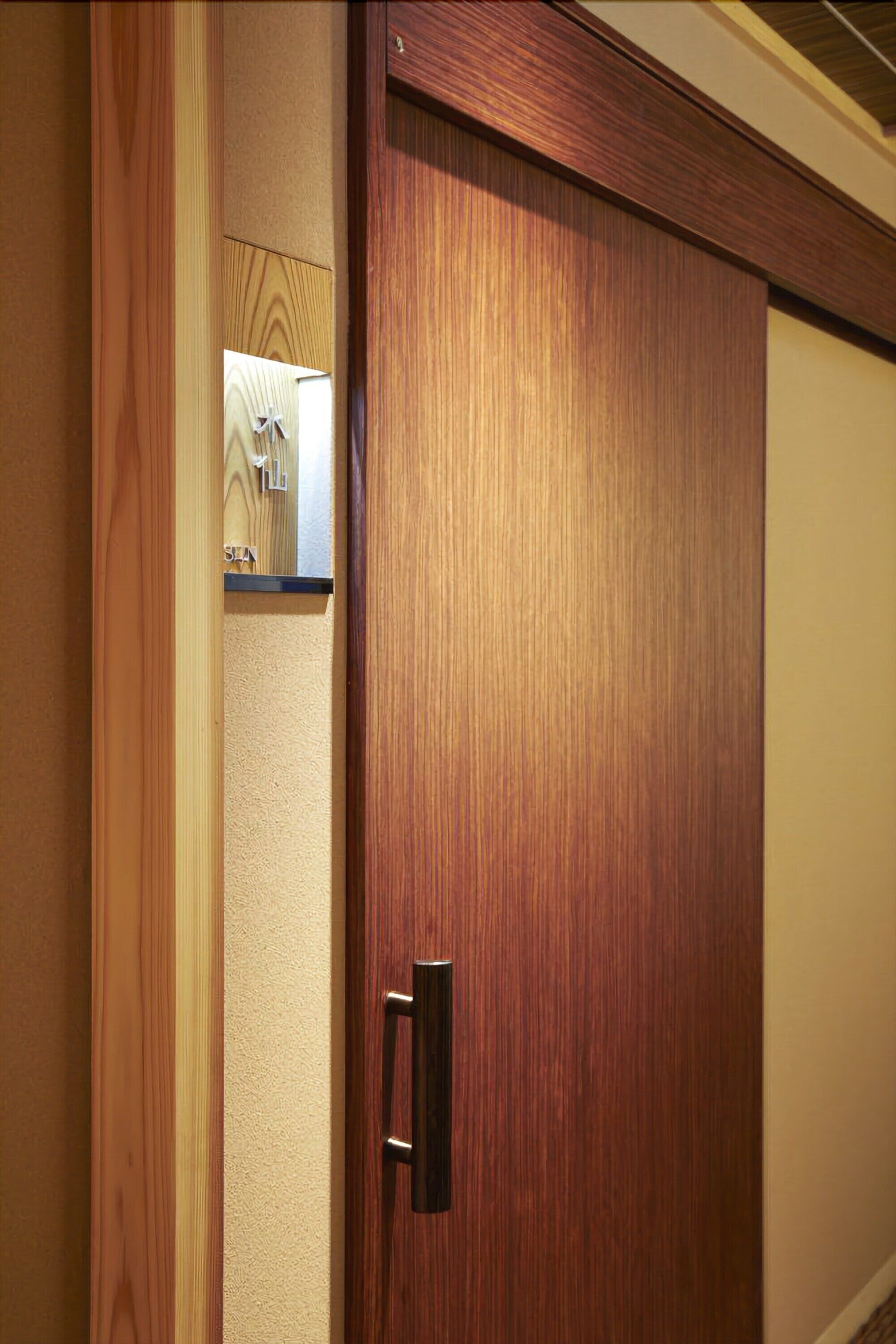 A wooden door with a handle, a small shelf with a box, and a textured wall.