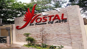 Un bâtiment avec une enseigne indiquant « HOSTAL San Francisco de Asis » et un logo représentant une feuille rouge.